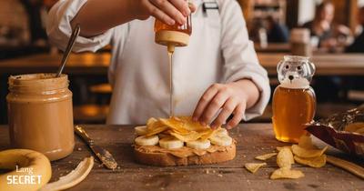 Мальчик готовит сэндвич в кафе в большом фартуке